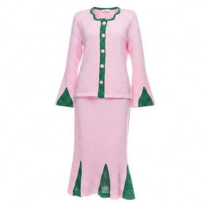 A pink two-piece skirt suit with green patterned trim and buttons.